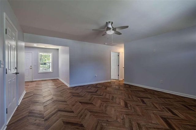 spare room with dark parquet floors and ceiling fan