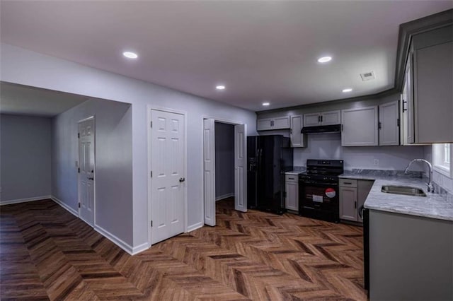 kitchen with gray cabinets, sink, black appliances, light stone countertops, and dark parquet flooring