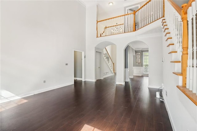 foyer entrance featuring crown molding, dark hardwood / wood-style floors, and a towering ceiling