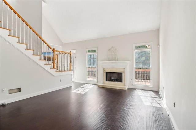 unfurnished living room featuring a wealth of natural light, high vaulted ceiling, and wood-type flooring