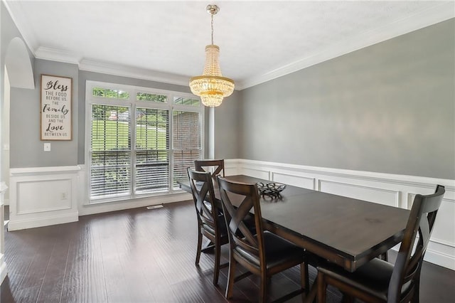 dining room with dark wood-type flooring, ornamental molding, and a chandelier