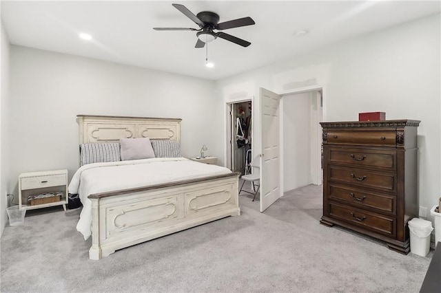 bedroom featuring a walk in closet, light carpet, ceiling fan, and a closet