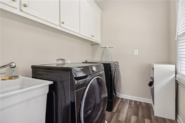 laundry room with sink, dark hardwood / wood-style floors, cabinets, and washing machine and clothes dryer