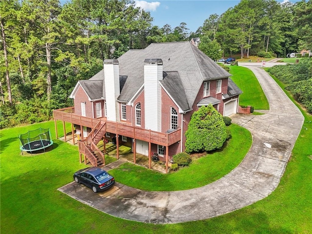 back of house with a trampoline, a wooden deck, a garage, and a yard