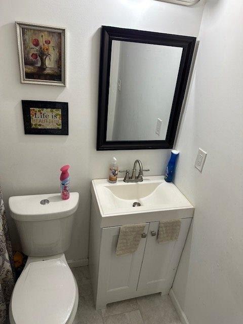 bathroom featuring toilet, tile patterned flooring, baseboards, and vanity