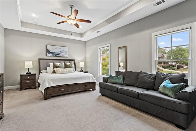 carpeted bedroom with a tray ceiling, ceiling fan, and ornamental molding