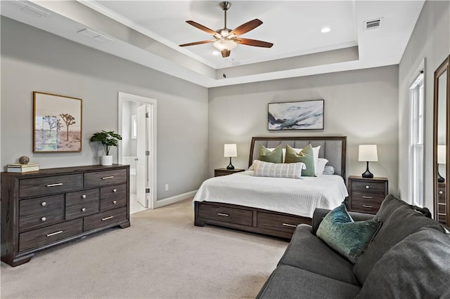 carpeted bedroom with a tray ceiling, ensuite bath, and ceiling fan