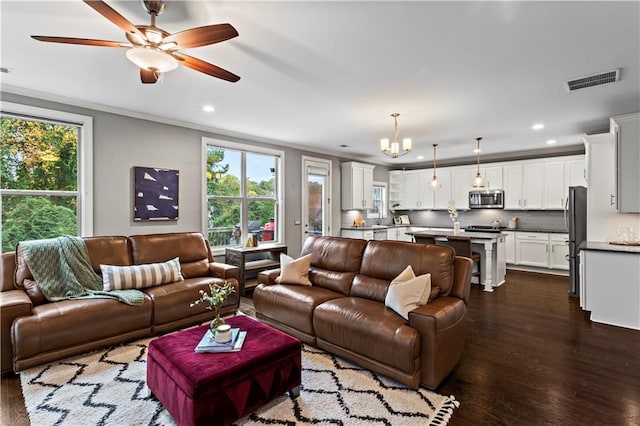 living room featuring dark hardwood / wood-style floors, ornamental molding, and ceiling fan with notable chandelier