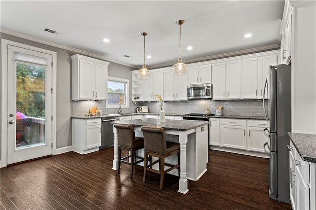 kitchen with a healthy amount of sunlight, a kitchen island, stainless steel appliances, and dark hardwood / wood-style floors