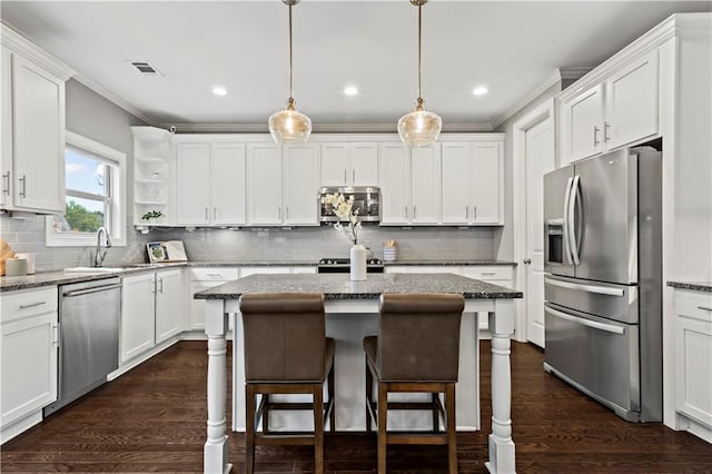 kitchen with appliances with stainless steel finishes, dark hardwood / wood-style flooring, light stone counters, pendant lighting, and white cabinetry