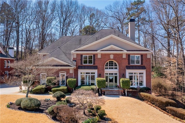 view of front of property with a chimney and brick siding