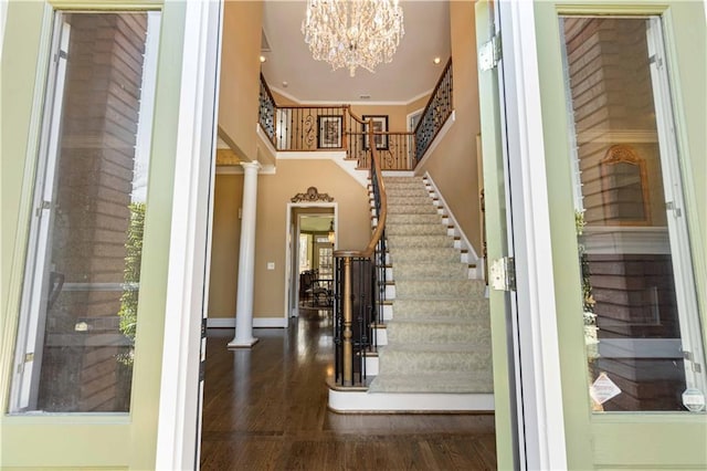 foyer entrance with ornate columns, stairway, ornamental molding, wood finished floors, and baseboards