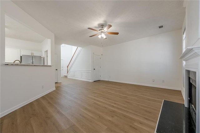 unfurnished living room with hardwood / wood-style flooring and ceiling fan