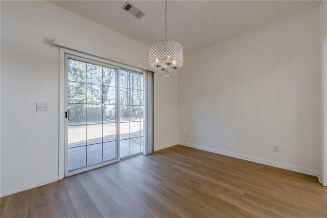 empty room with wood-type flooring and a notable chandelier