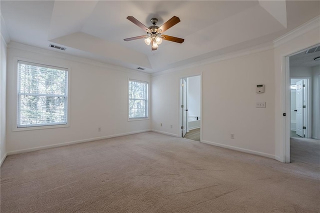 carpeted spare room featuring crown molding, ceiling fan, and a raised ceiling