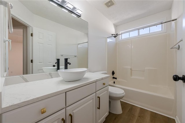 full bathroom with toilet, bathing tub / shower combination, a textured ceiling, vanity, and hardwood / wood-style flooring