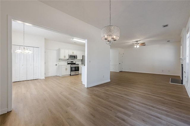 unfurnished living room with ceiling fan with notable chandelier and light wood-type flooring