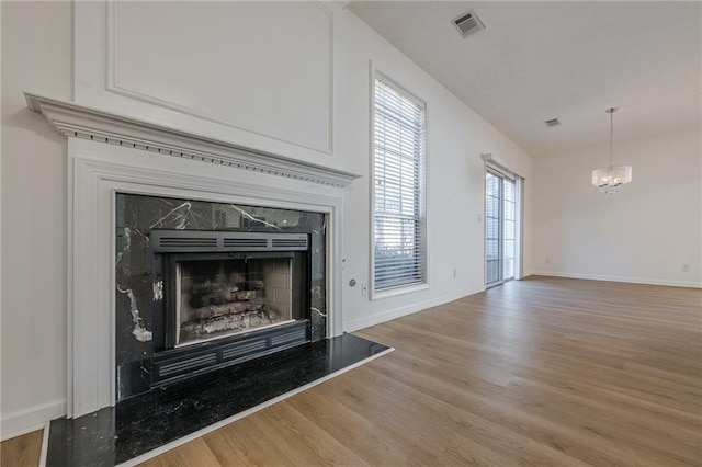 room details with hardwood / wood-style flooring, a high end fireplace, and a chandelier