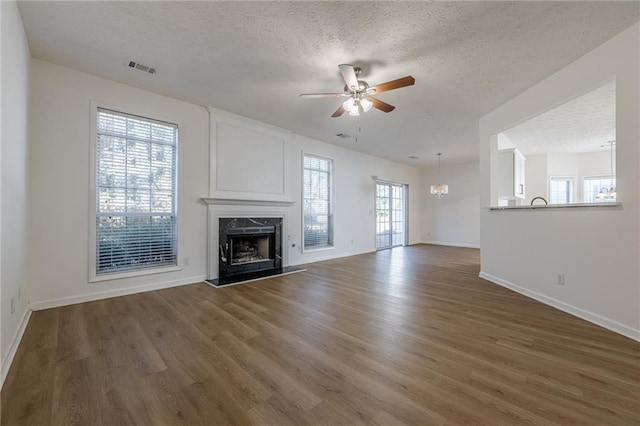 unfurnished living room featuring a textured ceiling, a high end fireplace, dark hardwood / wood-style floors, and ceiling fan