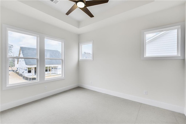 spare room with carpet, baseboards, a raised ceiling, and a ceiling fan