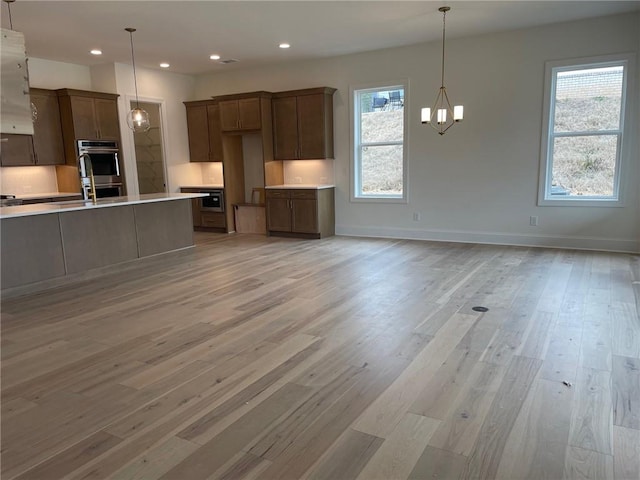 kitchen featuring an inviting chandelier, a healthy amount of sunlight, decorative light fixtures, and light hardwood / wood-style floors