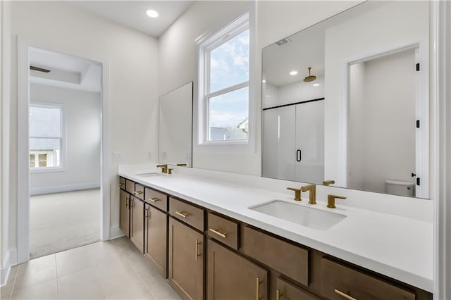 bathroom with double vanity, a stall shower, toilet, and a sink