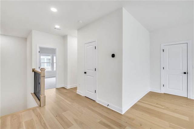 hall with recessed lighting, light wood-type flooring, an upstairs landing, and baseboards