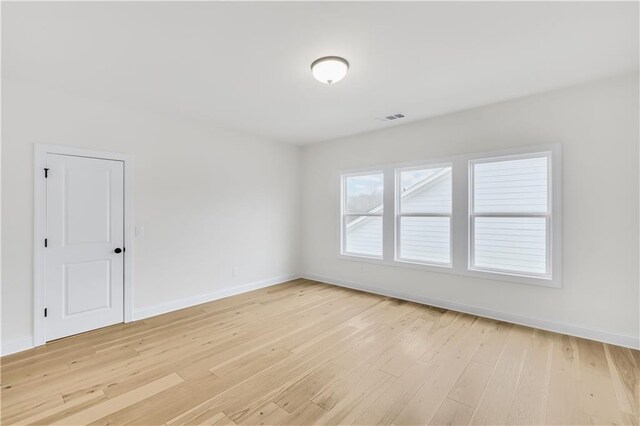 unfurnished room with light wood-style flooring, visible vents, and baseboards