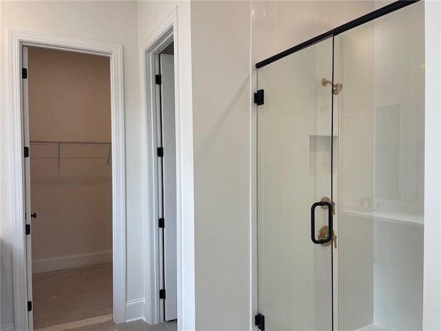 bathroom featuring a stall shower and a walk in closet