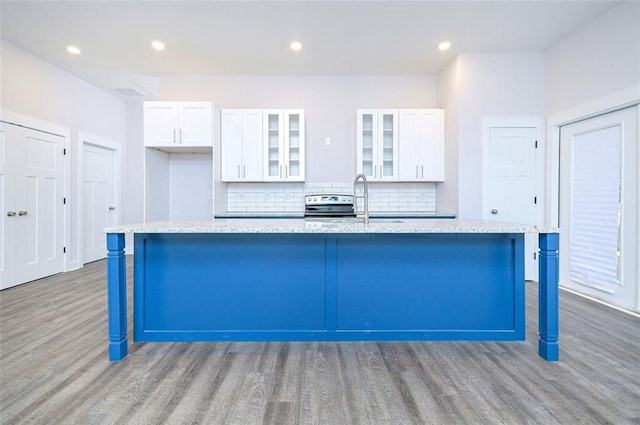 kitchen featuring tasteful backsplash, a breakfast bar, white cabinetry, and a center island with sink