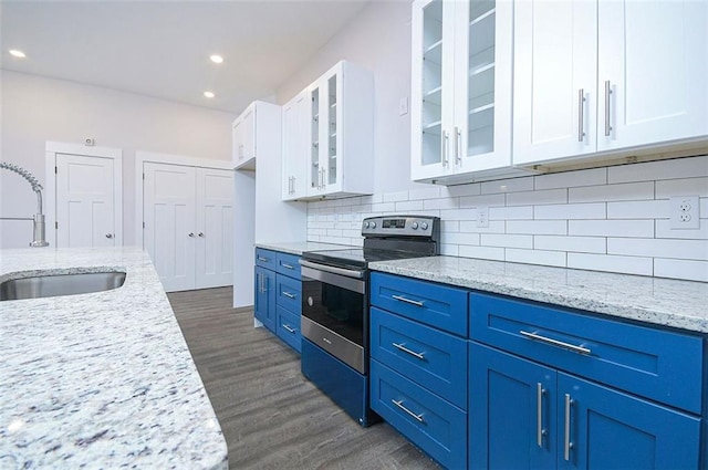 kitchen with light stone counters, blue cabinets, electric stove, sink, and white cabinetry