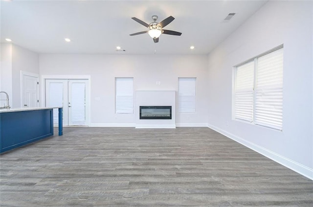 unfurnished living room featuring ceiling fan and dark wood-type flooring