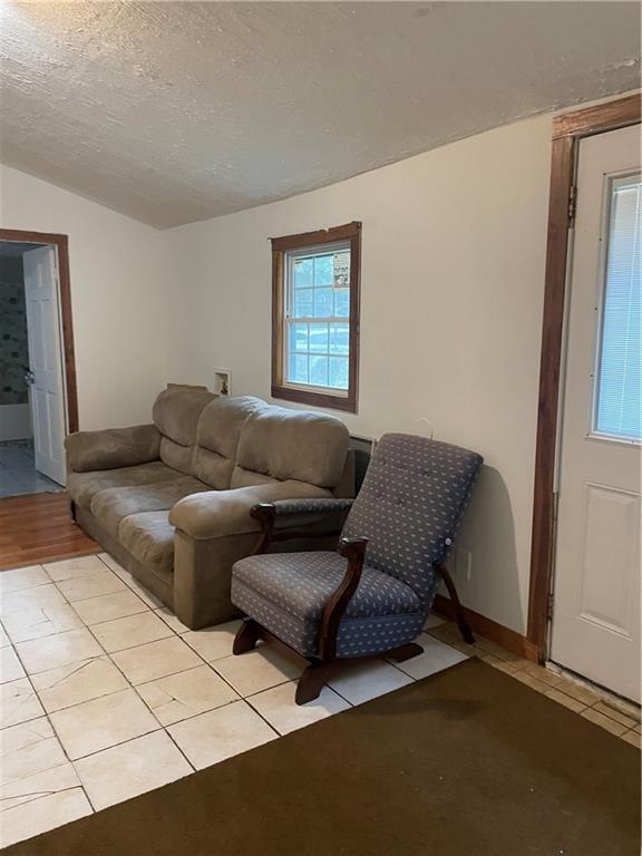 304 E 19th St SW, Rome, GA 30161 - living room with light tile patterned floors, lofted ceiling, a textured ceiling, and baseboards