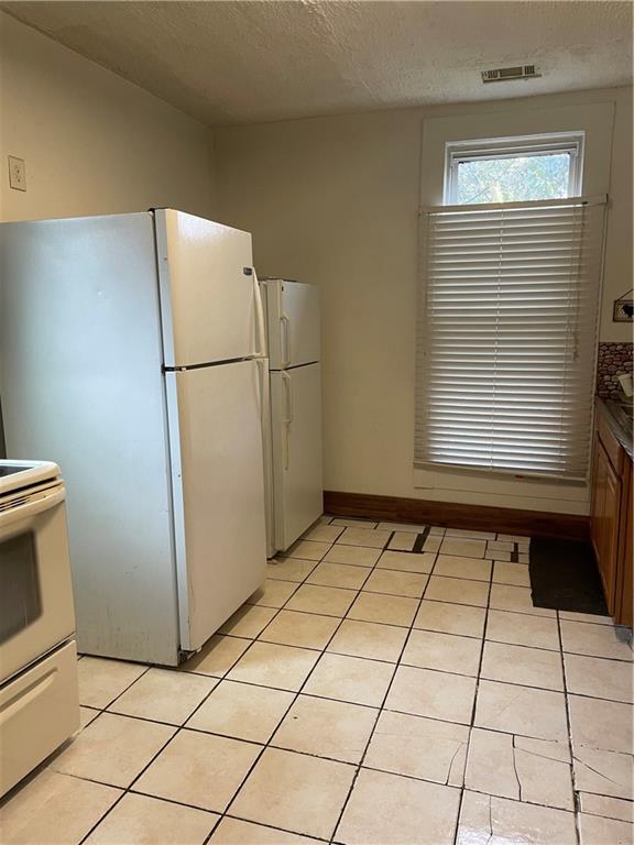 304 E 19th St SW, Rome, GA 30161 - kitchen with white appliances, light tile patterned floors, a textured ceiling, and baseboards