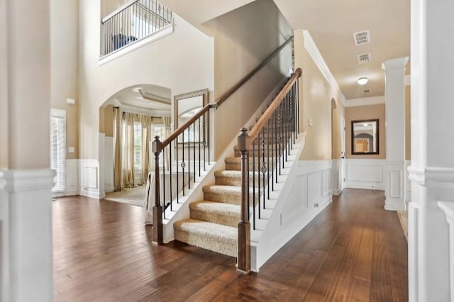 stairway featuring decorative columns, ornamental molding, and hardwood / wood-style floors