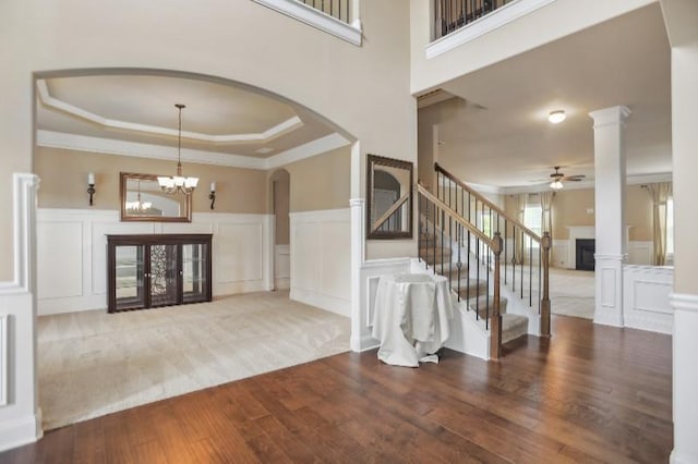 foyer with crown molding, wood-type flooring, a tray ceiling, and ceiling fan with notable chandelier