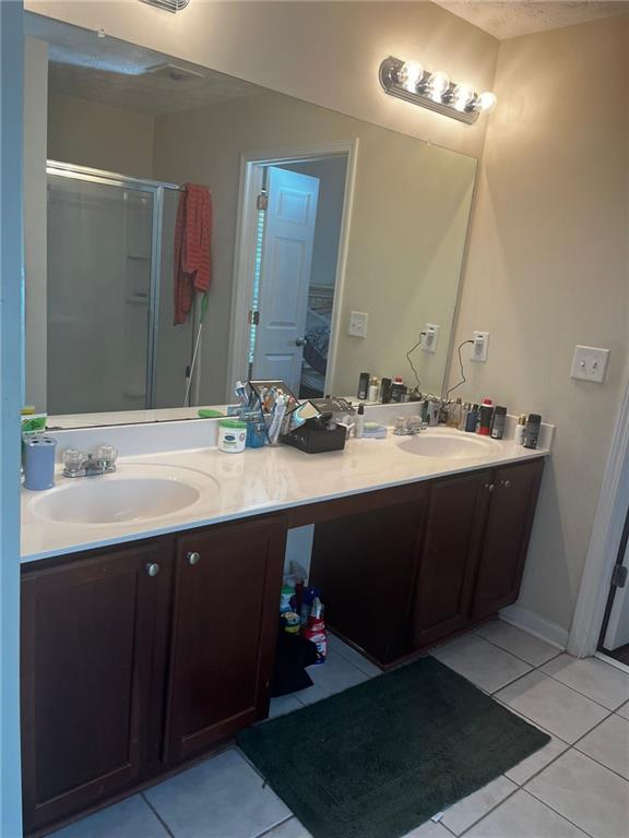 bathroom with walk in shower, tile patterned flooring, and vanity