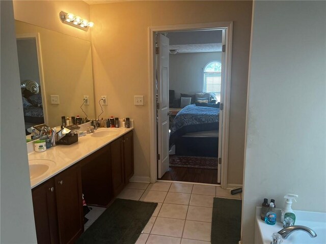 bathroom with a bathing tub, vanity, and tile patterned floors