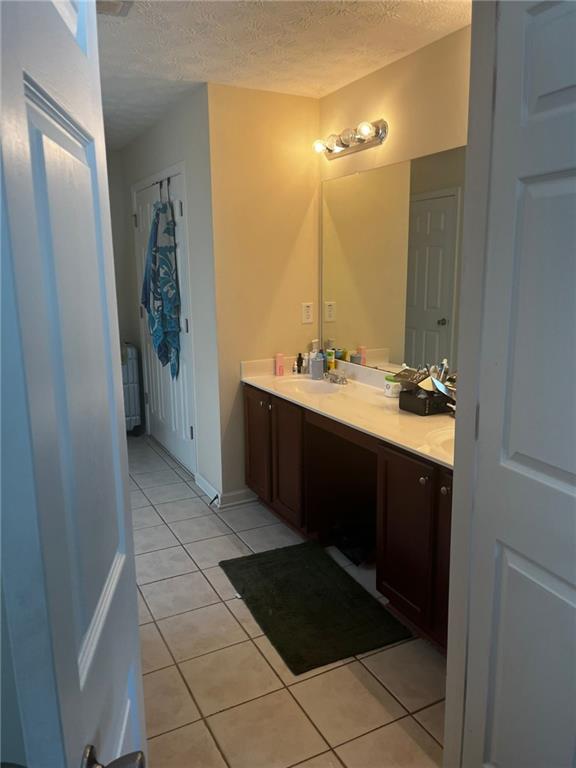 bathroom with vanity, a textured ceiling, and tile patterned flooring