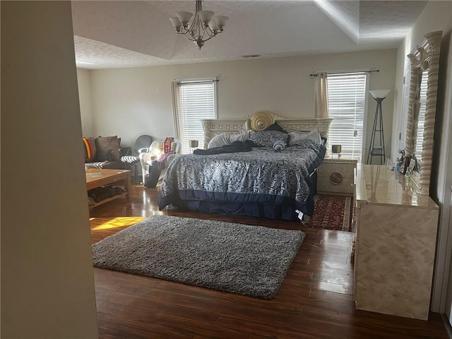 bedroom featuring an inviting chandelier, multiple windows, a textured ceiling, and dark hardwood / wood-style flooring