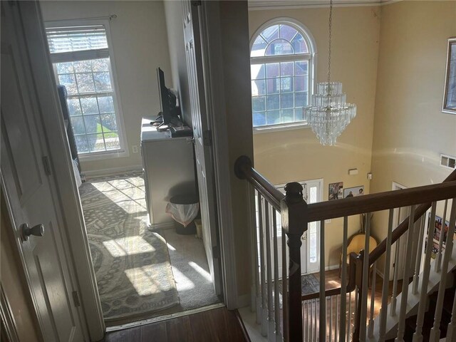 stairs with hardwood / wood-style floors and an inviting chandelier