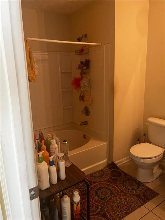 bathroom featuring shower / tub combination, tile patterned flooring, and toilet