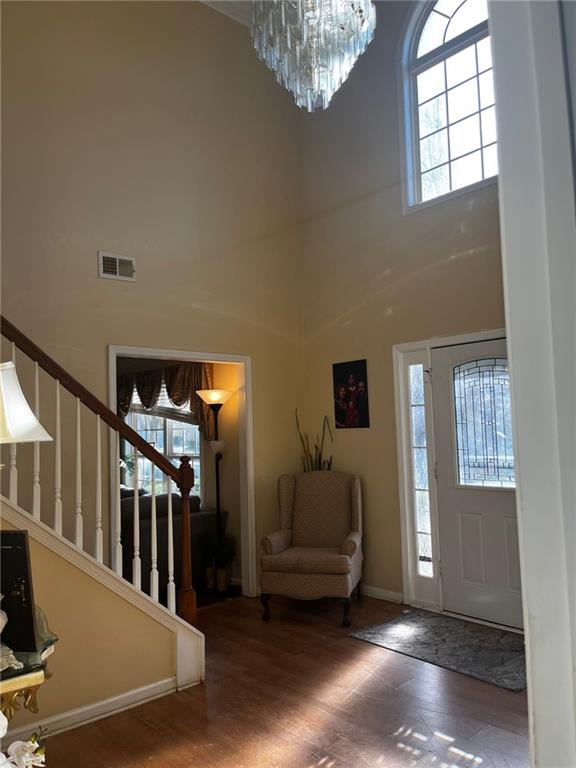 entrance foyer with a high ceiling, hardwood / wood-style flooring, and a notable chandelier