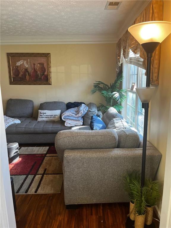 living room featuring dark hardwood / wood-style flooring, a textured ceiling, and crown molding