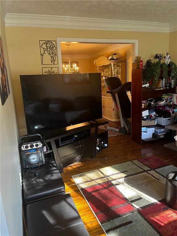 living room featuring hardwood / wood-style flooring, an inviting chandelier, and crown molding