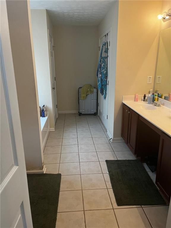 bathroom with vanity, a textured ceiling, tile patterned floors, and a bath