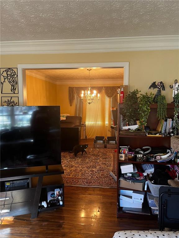 interior space with an inviting chandelier, a textured ceiling, hardwood / wood-style flooring, and ornamental molding