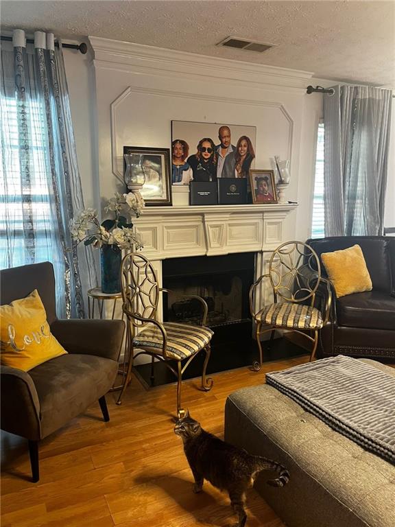 living area with a textured ceiling, light hardwood / wood-style flooring, and ornamental molding