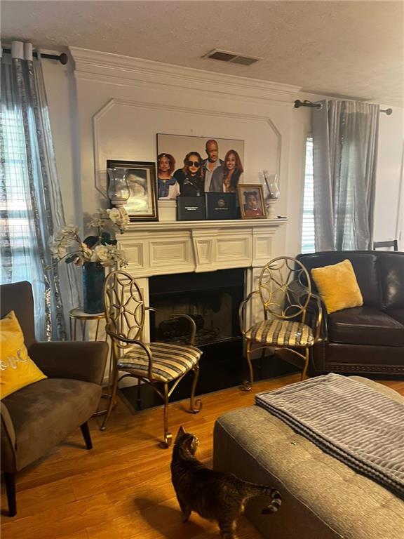 living area with light hardwood / wood-style floors, a textured ceiling, and crown molding