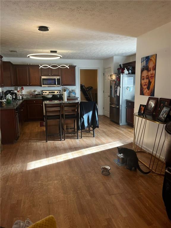 kitchen with a textured ceiling, light hardwood / wood-style flooring, and appliances with stainless steel finishes